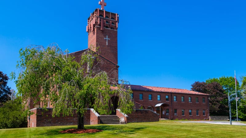 Exterior of red-brick facility with a lan and walkway to entrance.