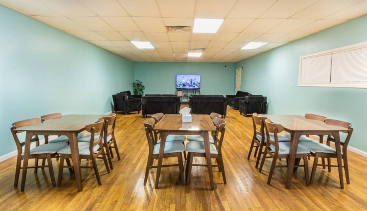 Large group room with tables, chairs, couches, and TV
