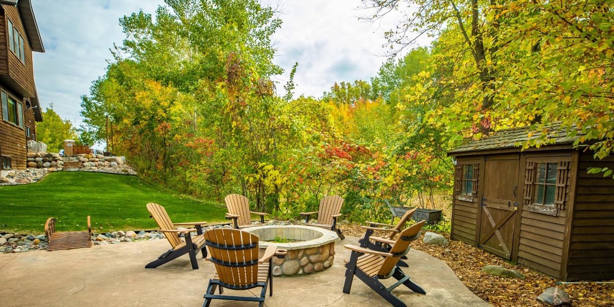 Outdoor firepit with wooden chairs surrounded by trees