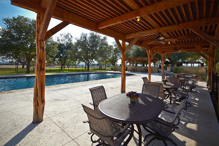 Covered patio with tables beside the swimming pool