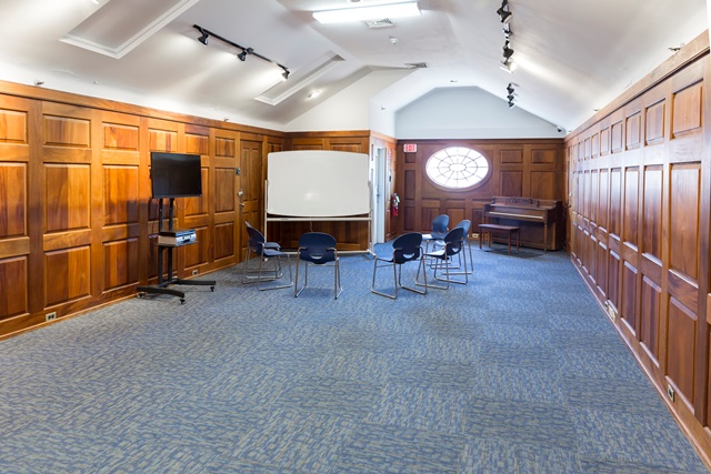 Wood-paneled therapy room with chairs and whiteboard