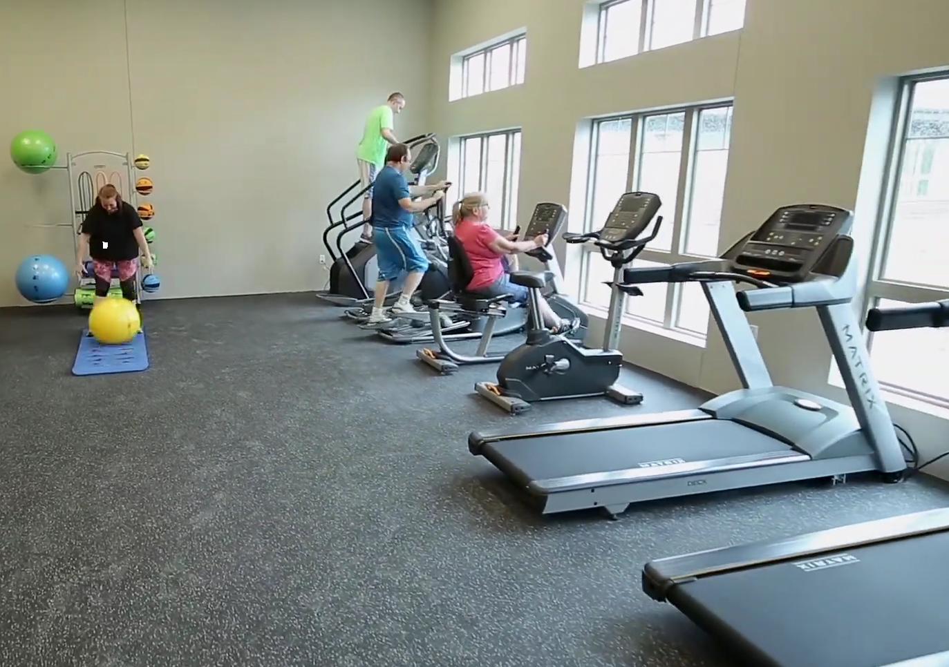 Clients using treadmills and bikes in rehab gym
