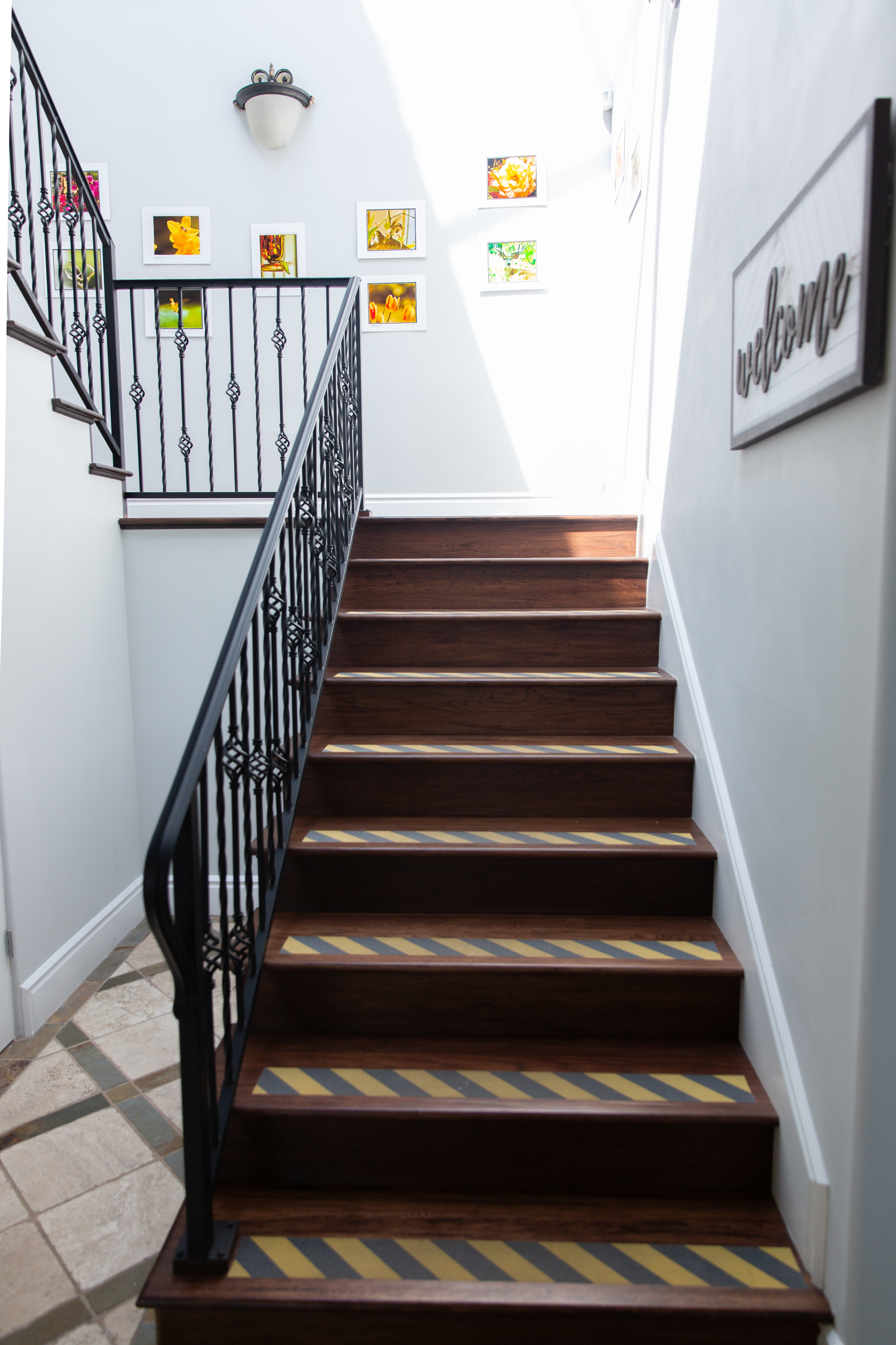 Wooden staircase with black railing and welcome wall decor