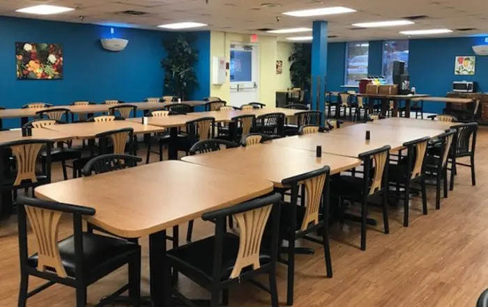 Dining hall with rows of wood tables and black chairs
