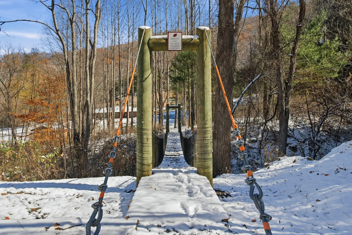 Wooden suspension bridge crossing wooded area on property