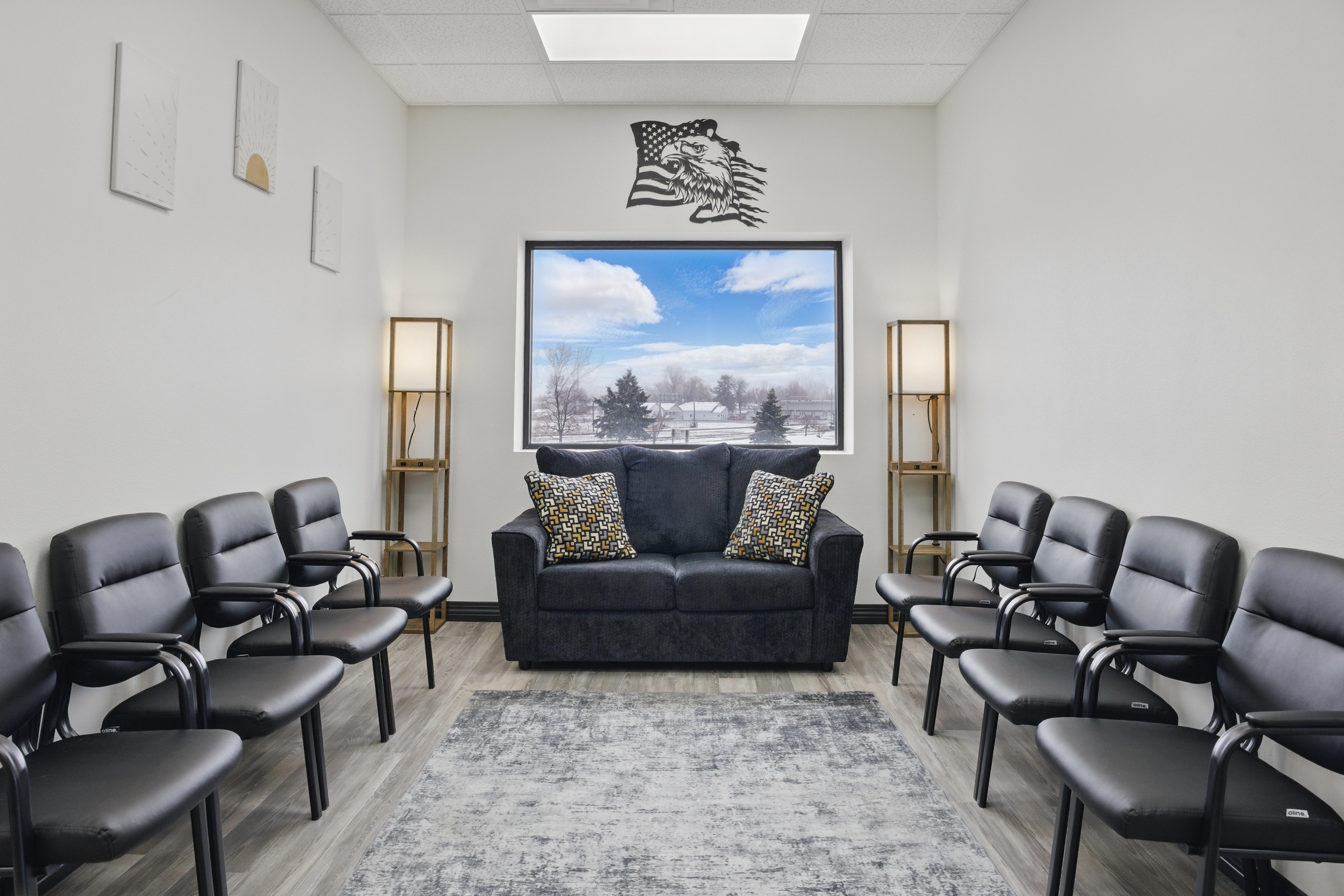 Waiting area with black chairs, couch, and large window