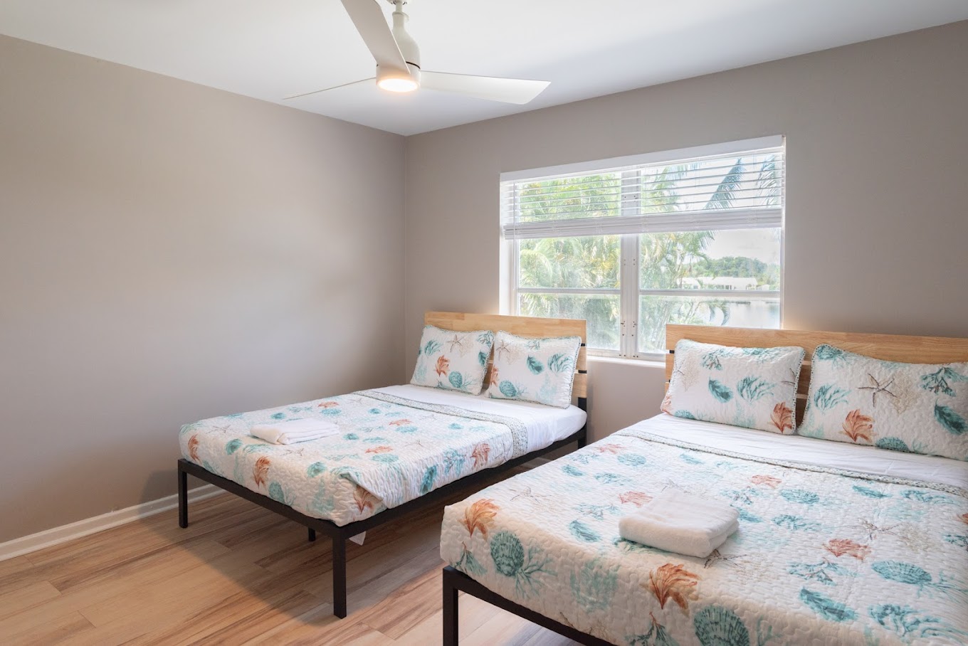 Two beds in bright room with palm tree views