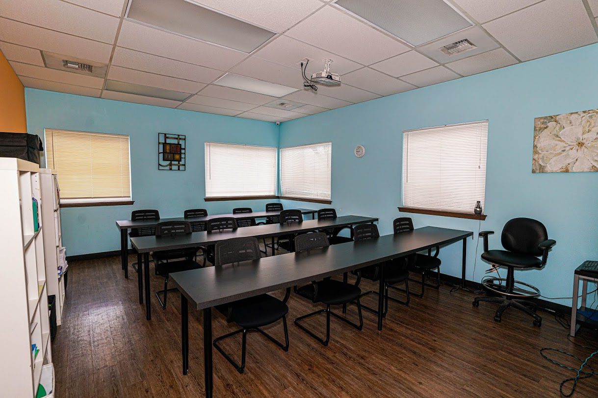 Blue therapy room with long tables and black chairs