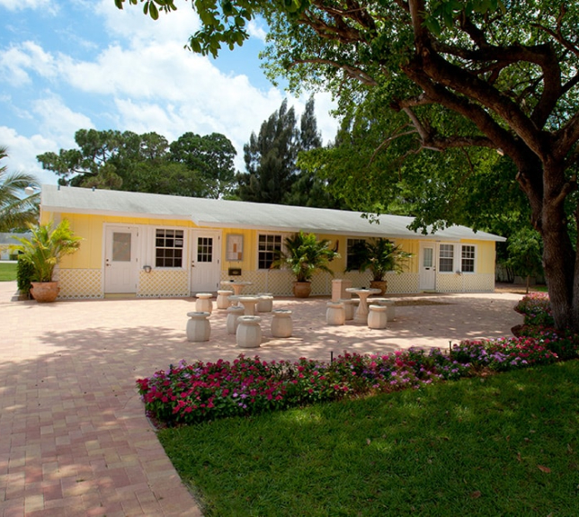 Yellow building with outdoor seating and lush greenery.