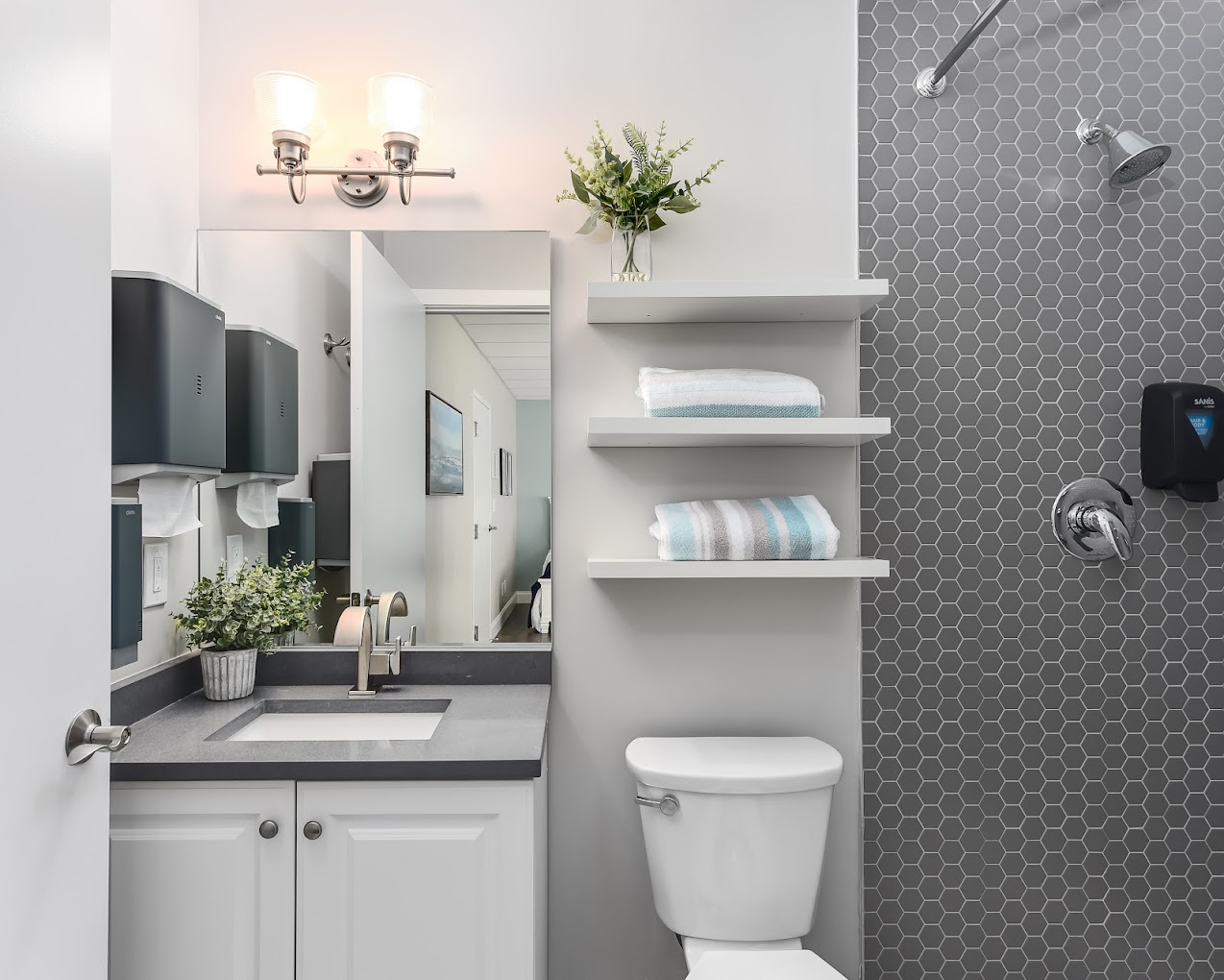 Rehab bathroom with sink, toilet, towels, and tiled shower