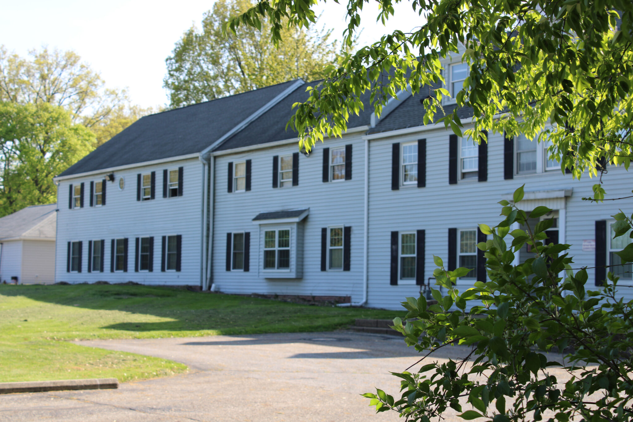 Two-story white residential building with black shutters
