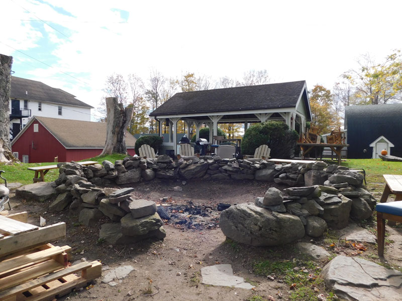 Outdoor seating area with stone fire pit and covered pavilion