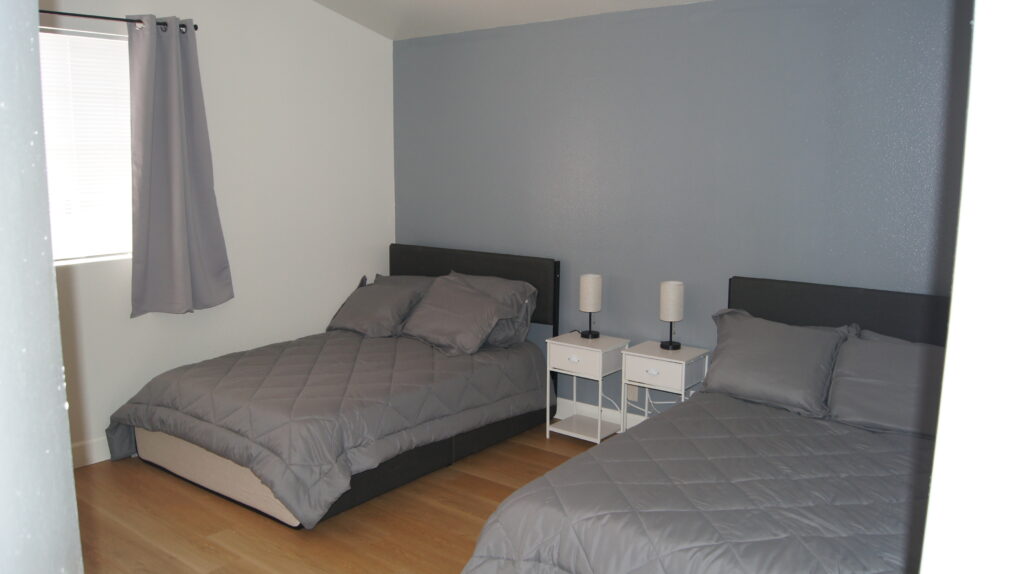 Two beds with gray bedding in a shared rehab bedroom