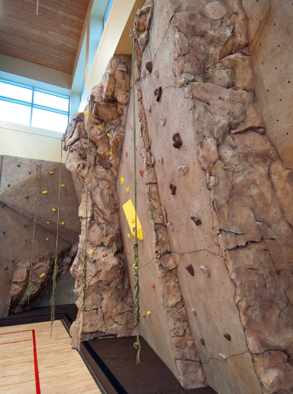 Indoor rock climbing wall with safety ropes and padded flooring