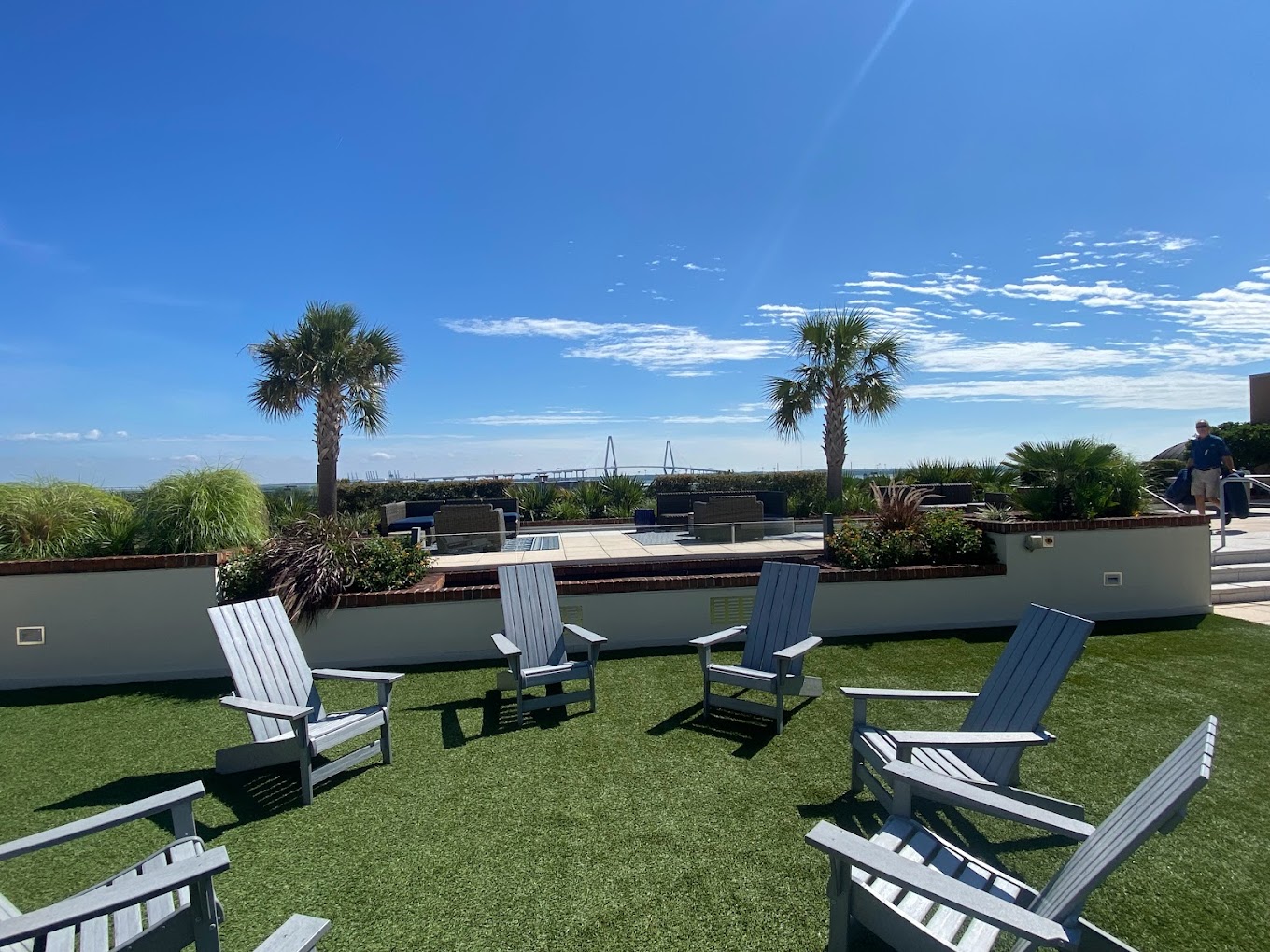Outdoor seating area with Adirondack chairs and palm trees.