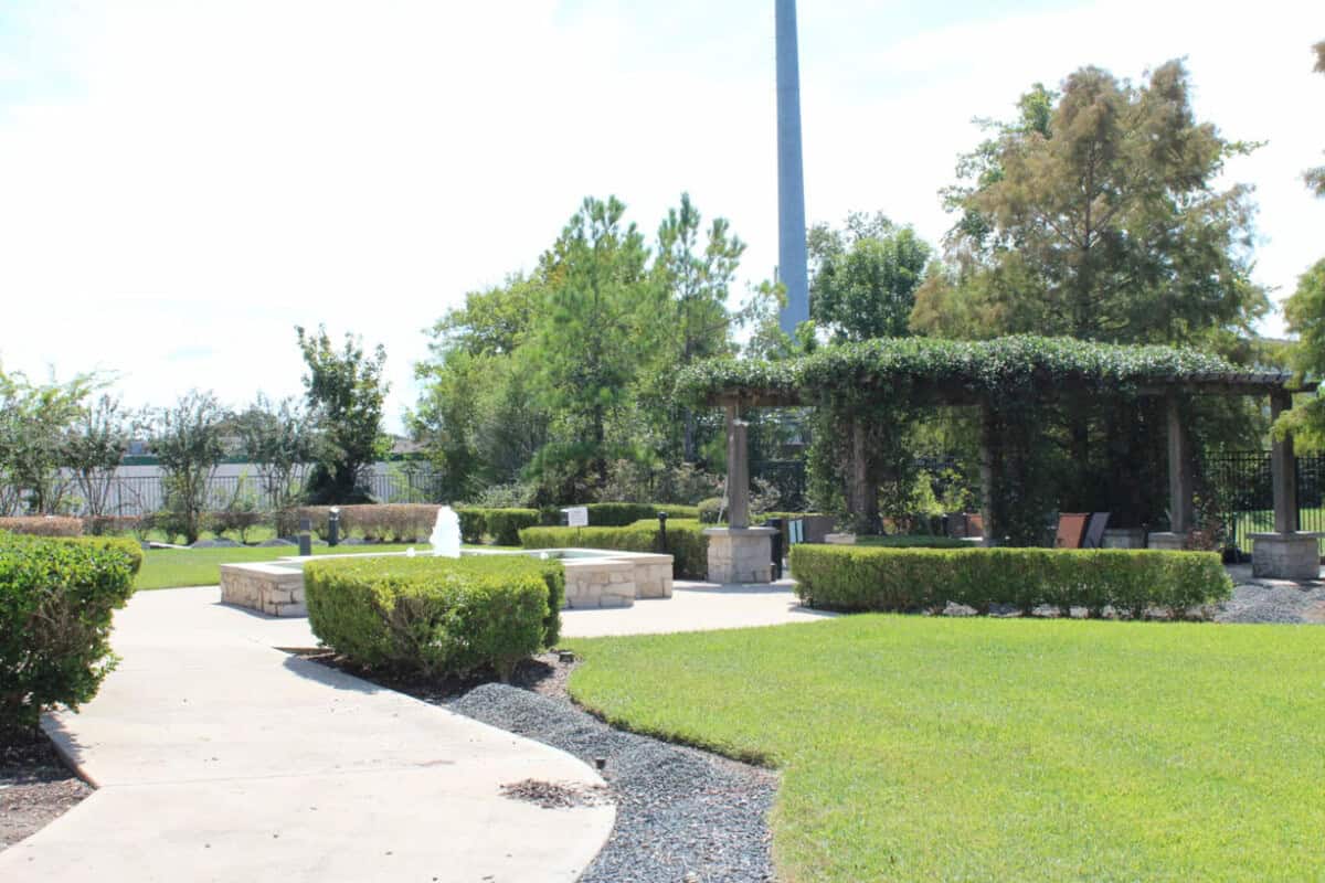 Outdoor garden with a fountain, seating area aroung greenery.