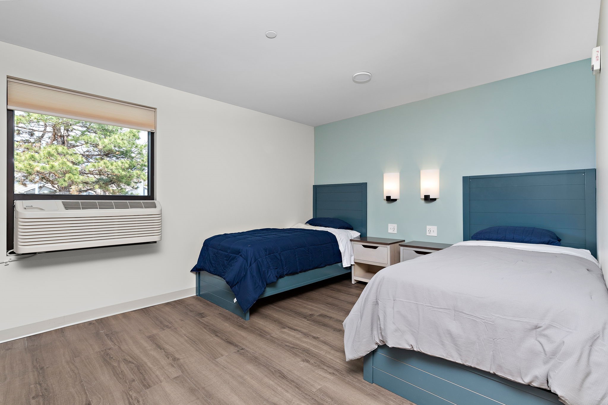 Room with two beds and a window AC unit