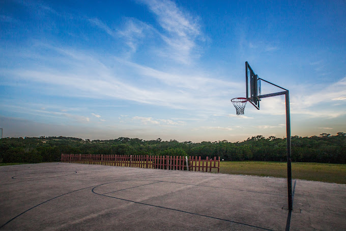 Concrete court with hoop overlooking trees and sky