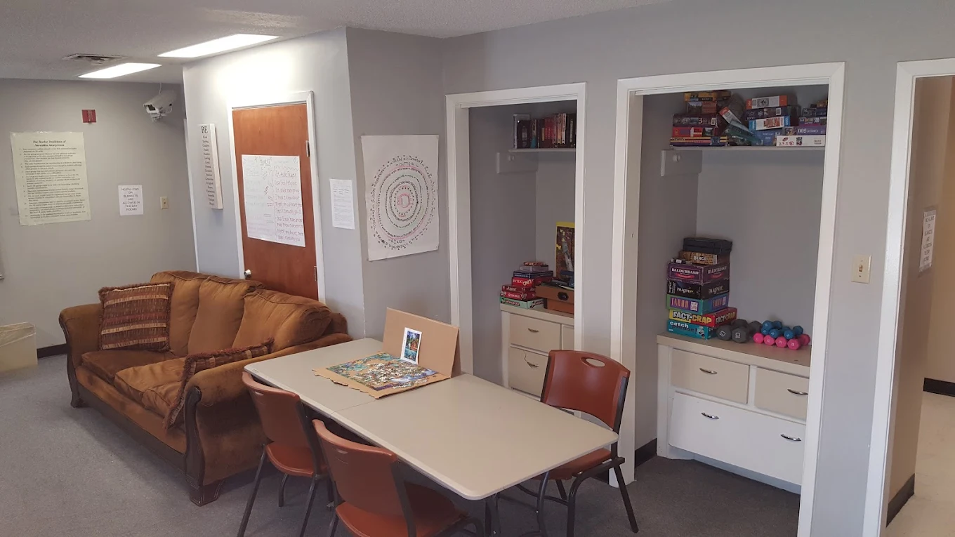 Common room with sofa, table, and shelves of board games.