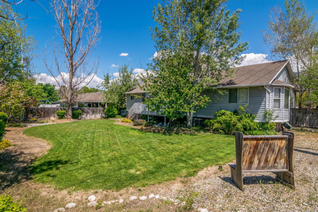 Spacious backyard with lawn, trees, and seating area