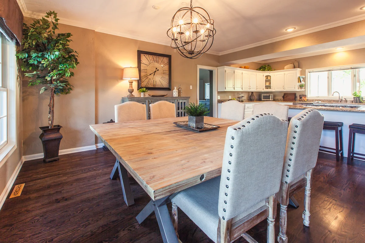Rustic-style dining room with a large wooden table, upholstered chairs, and decorative chandelier next to the open kitchen