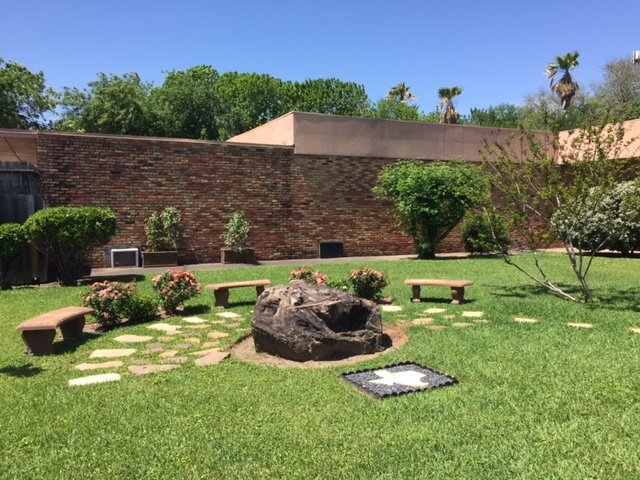 Outdoor garden with benches and central rock feature