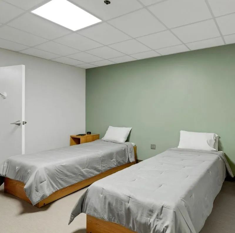 Room with two beds and a light green accent wall