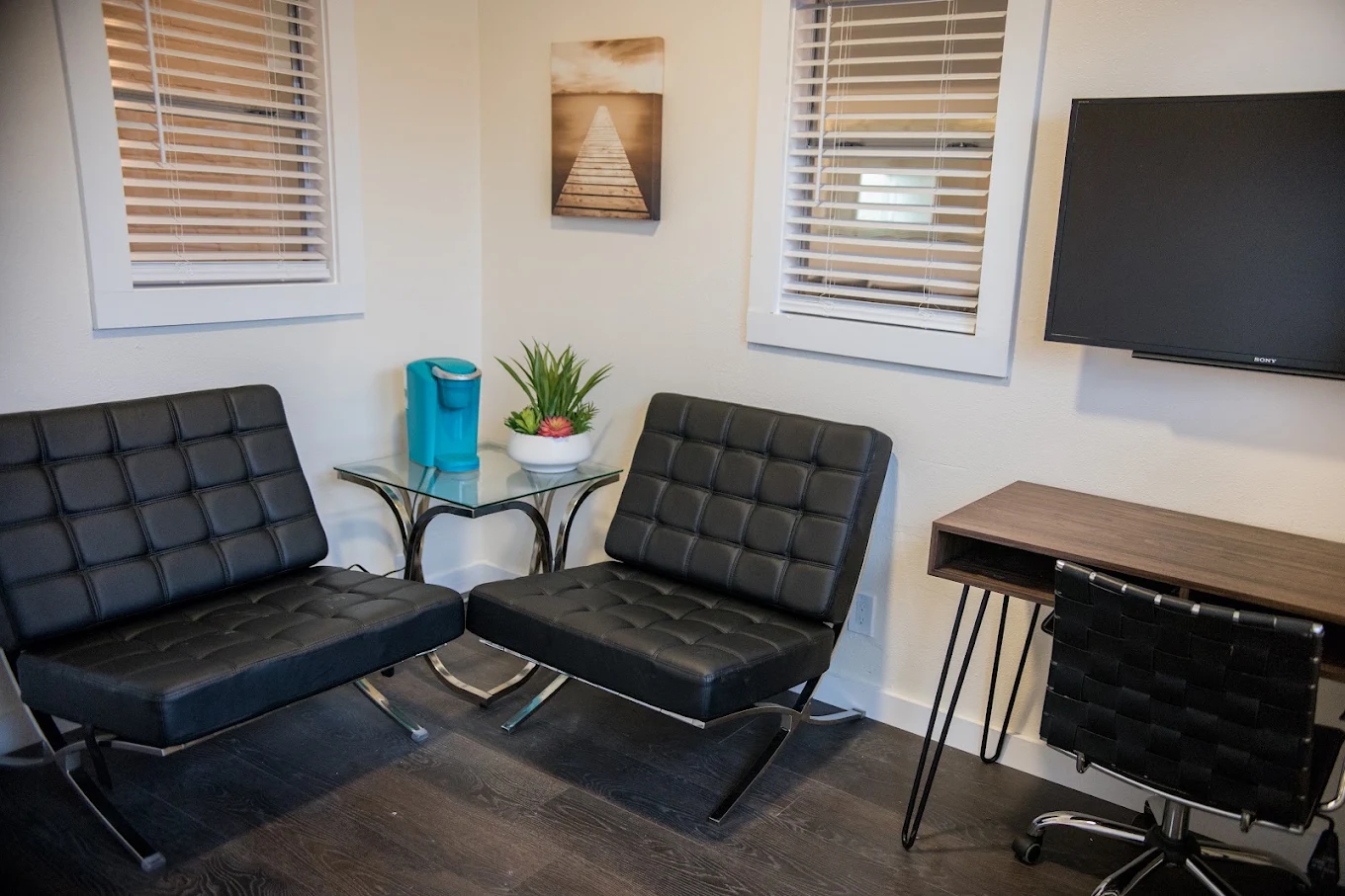 Private therapy room with chairs, desk, and wall-mounted TV
