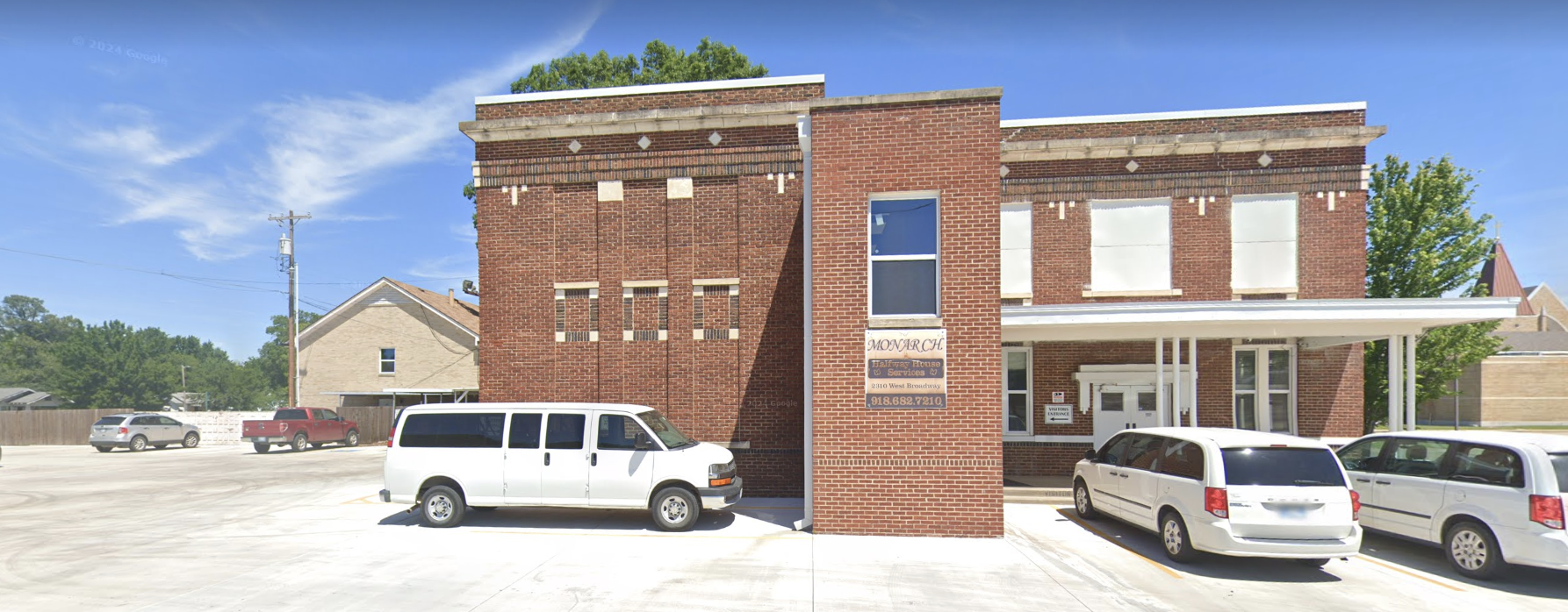 Brick rehab facility with a welcoming entrance, surrounded by a spacious parking area.