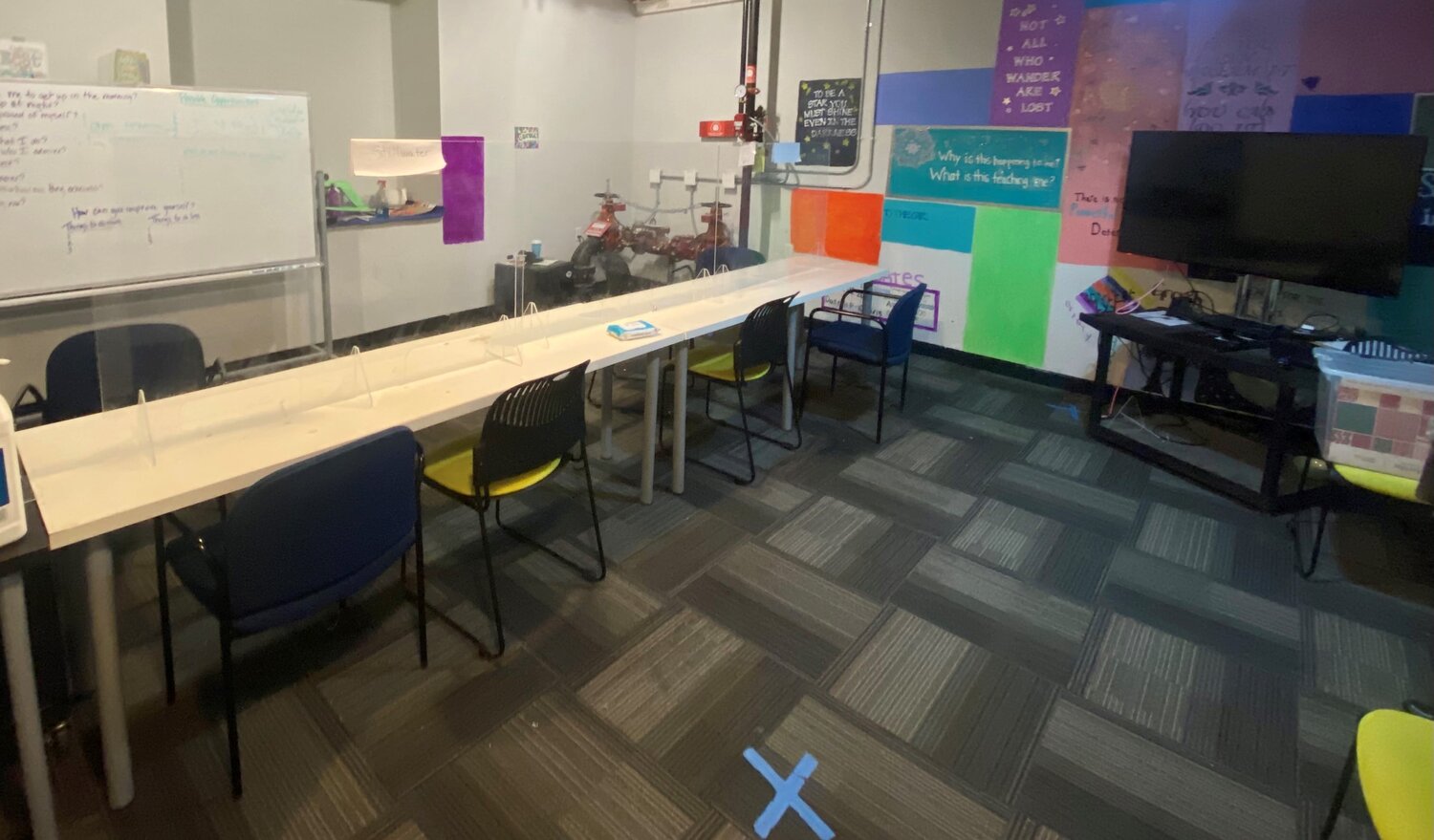 Group therapy room with long table and whiteboard wall art