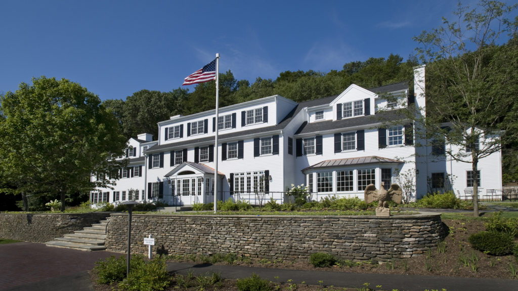 White colonial-style hospital building surrounded by trees and greenery