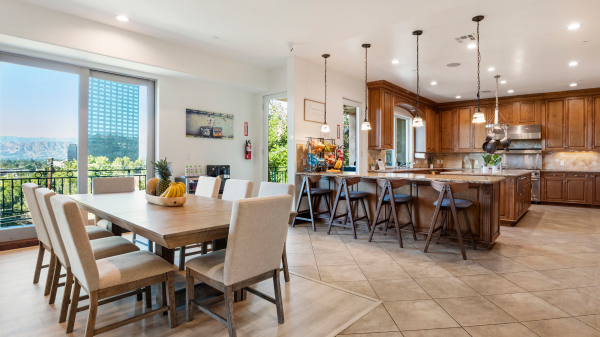 Large open kitchen with wooden cabinetry, island seating, and dining table overlooking scenic view