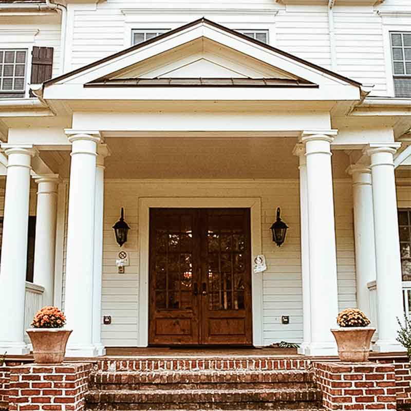 Front entrance with columns, brick steps, and double wooden doors