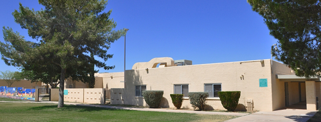 Beige treatment center building with trees and trimmed shrubs