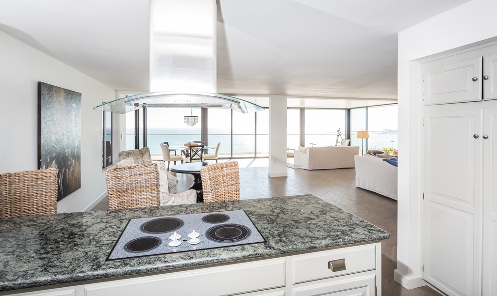 Kitchen with island stove and ocean view in the background.