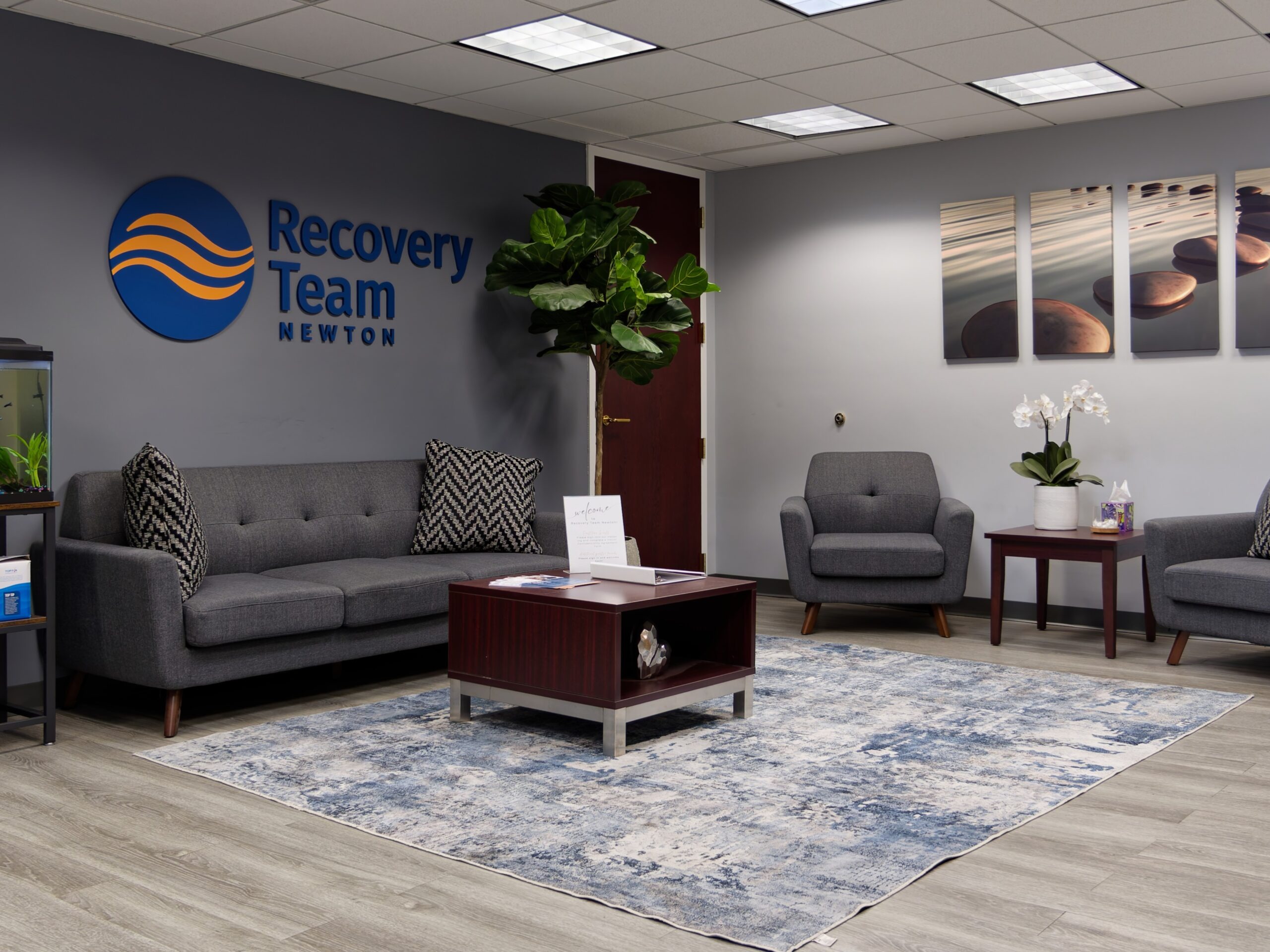 Modern lobby with gray seating, decor, and Recovery Team logo.