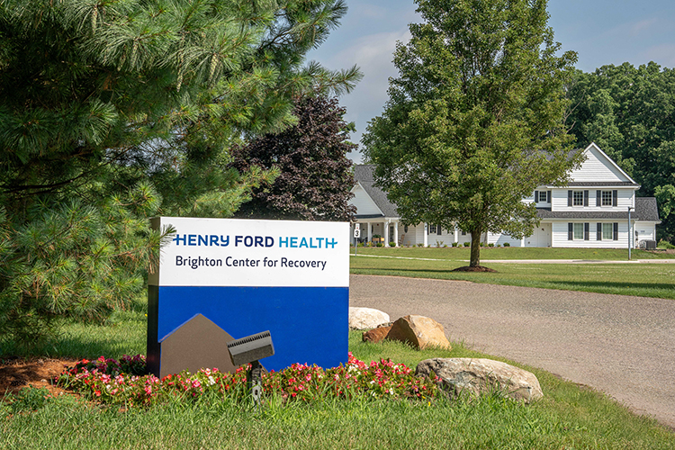 Facility sign near driveway with building in background