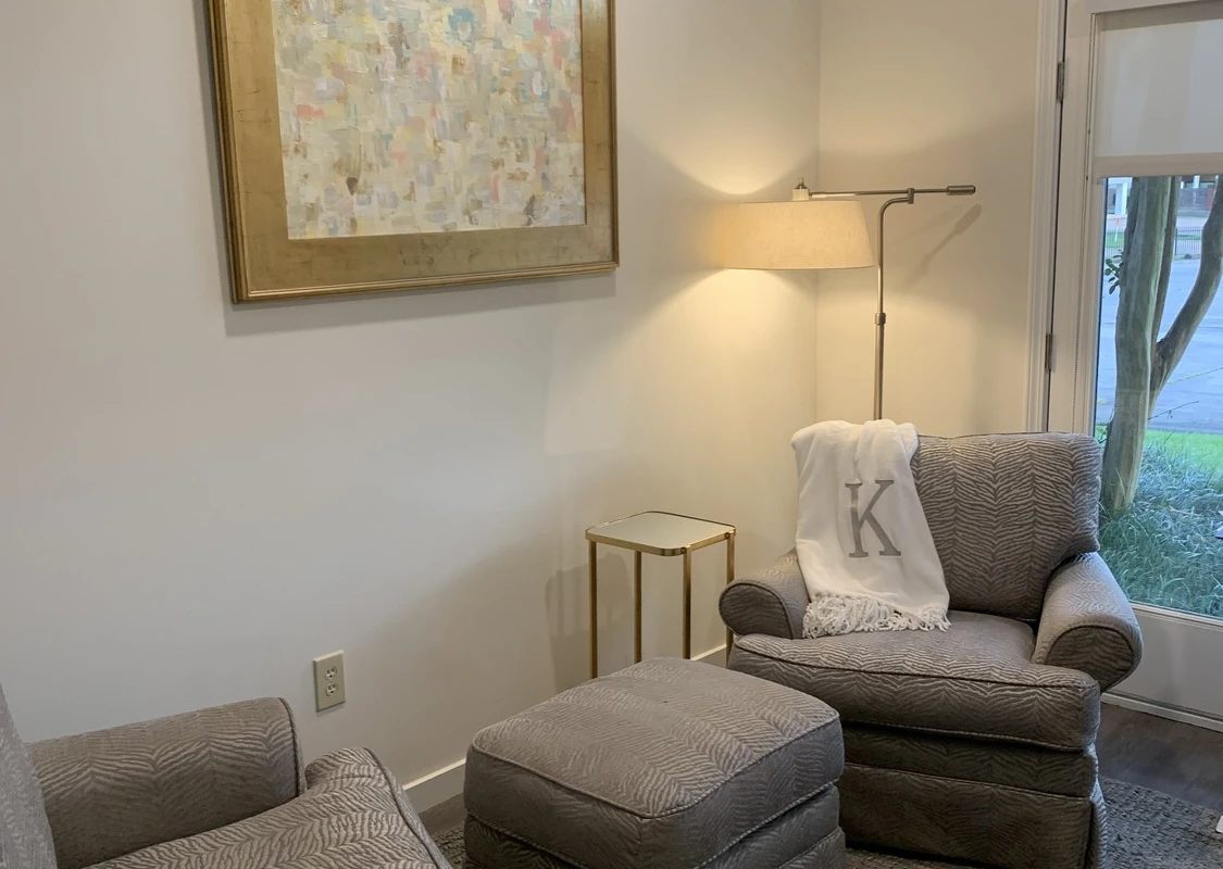 Two armchairs with ottoman beside a window and floor lamp