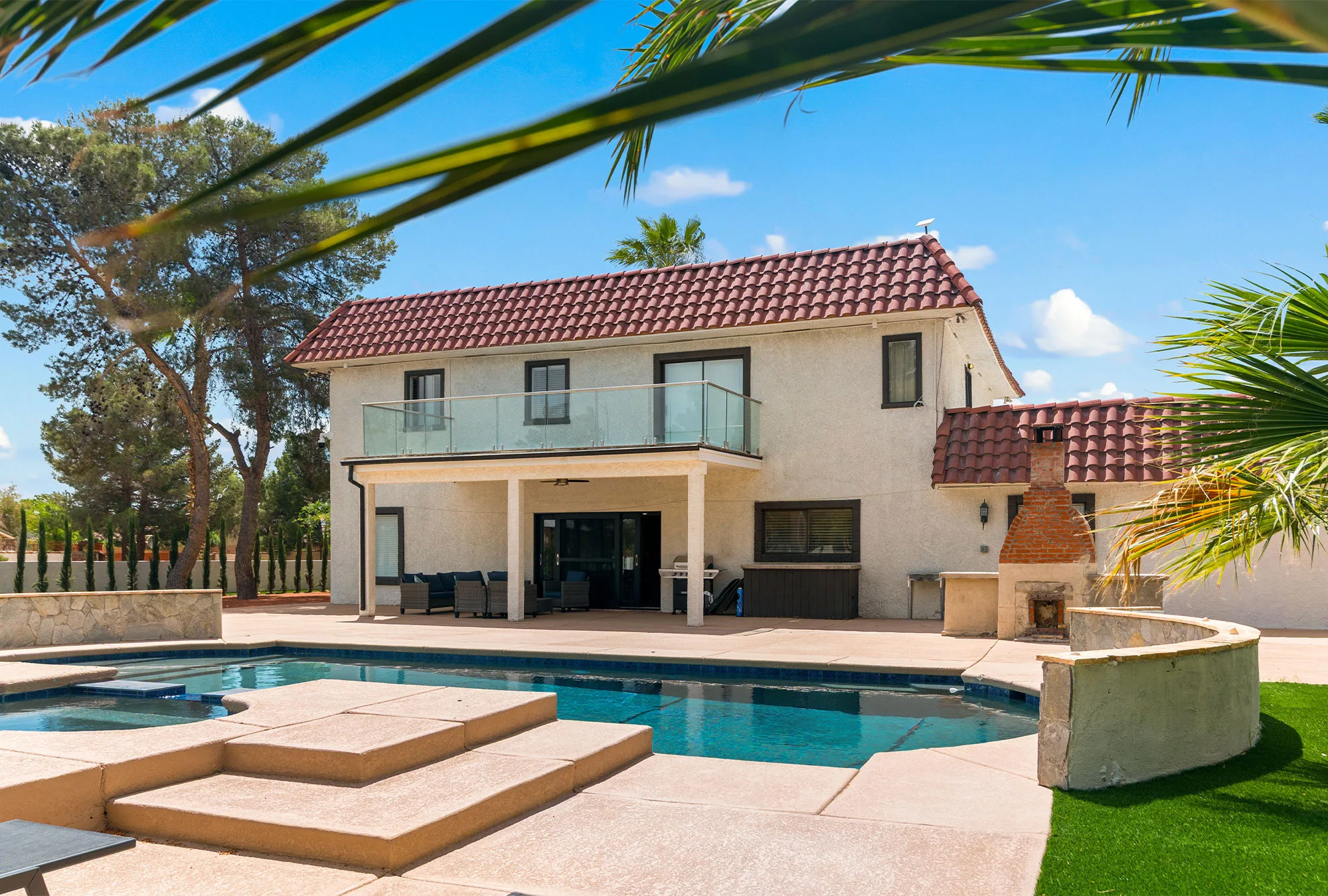 Outdoor pool with patio seating and palm trees