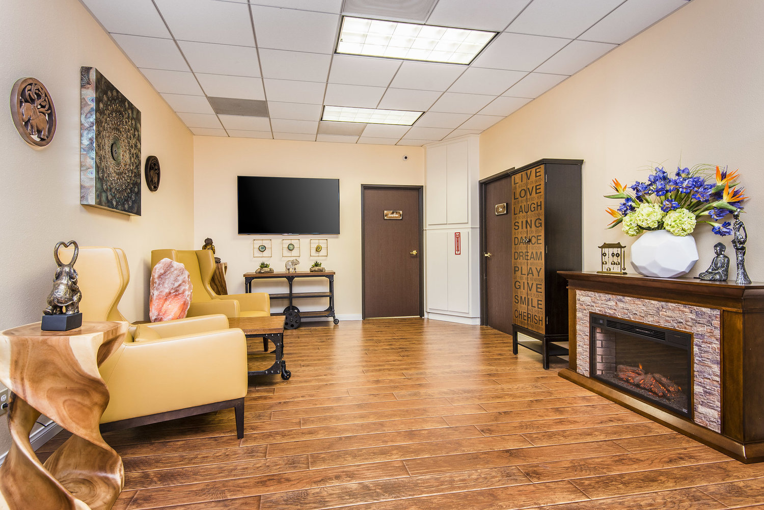 Lounge with yellow chairs, fireplace, and large TV