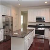 Modern kitchen with white cabinets and stainless steel appliances.