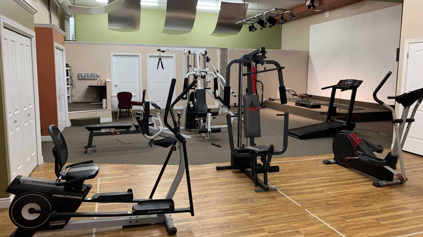 Residential gym with cardio machines and strength equipment.