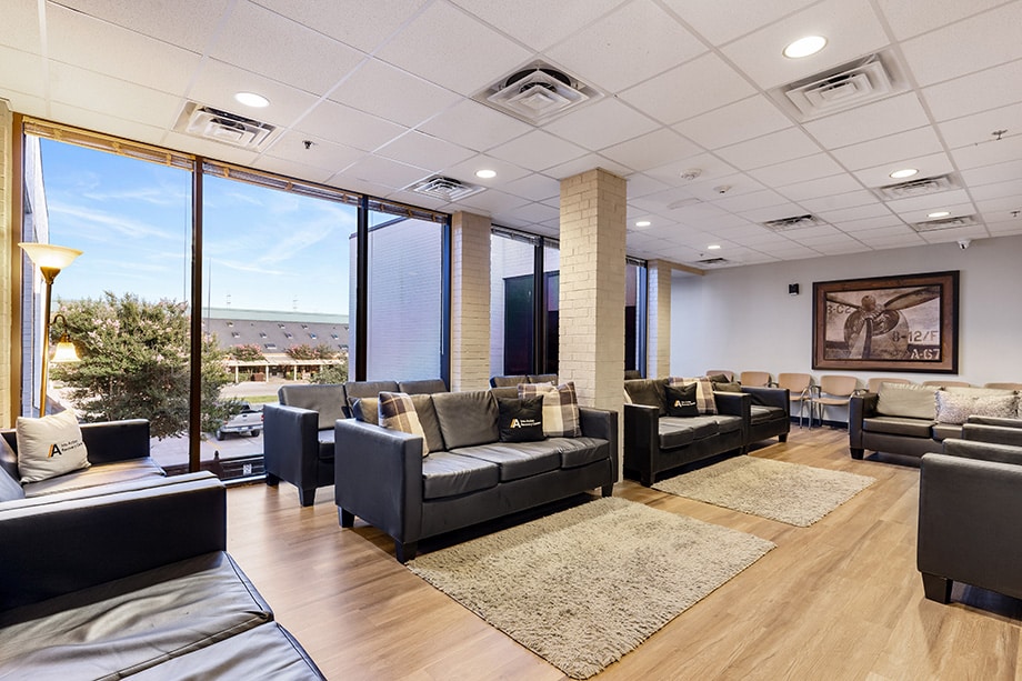 Large waiting room with black leather couches and floor-to-ceiling windows