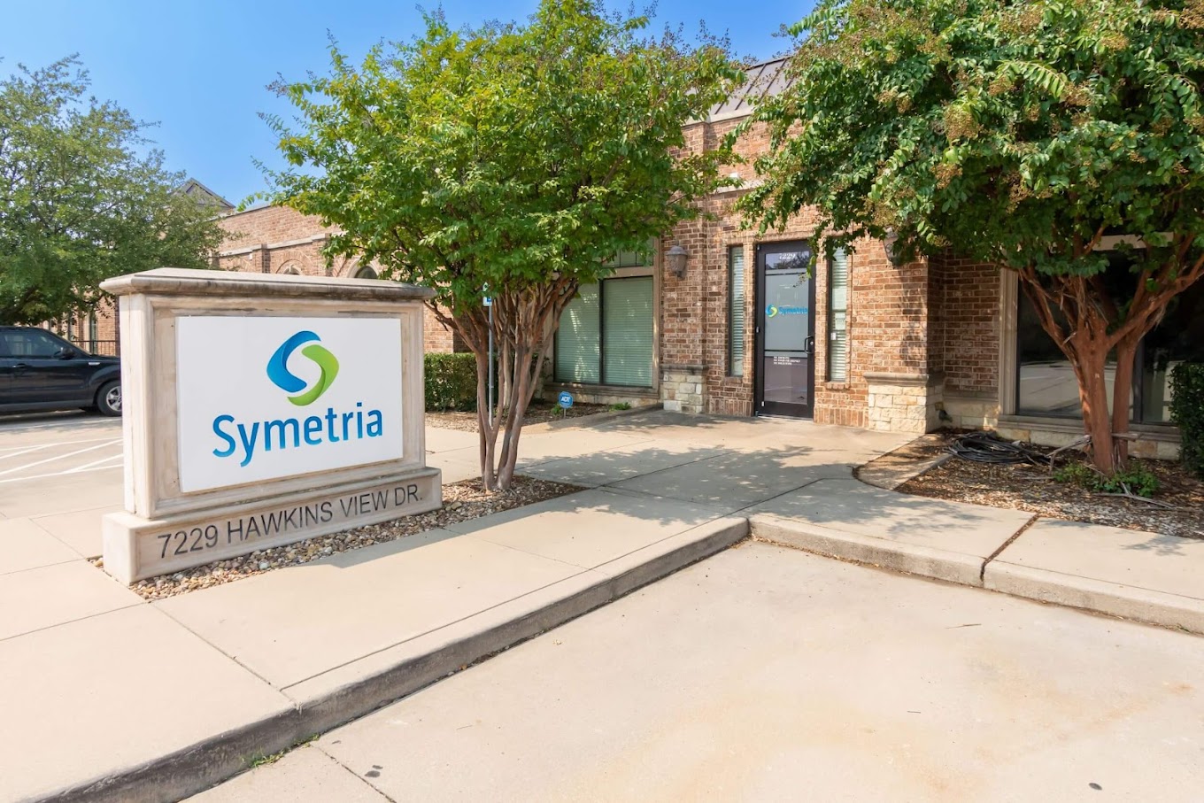 Exterior of Symetria Recovery with signage and trees.