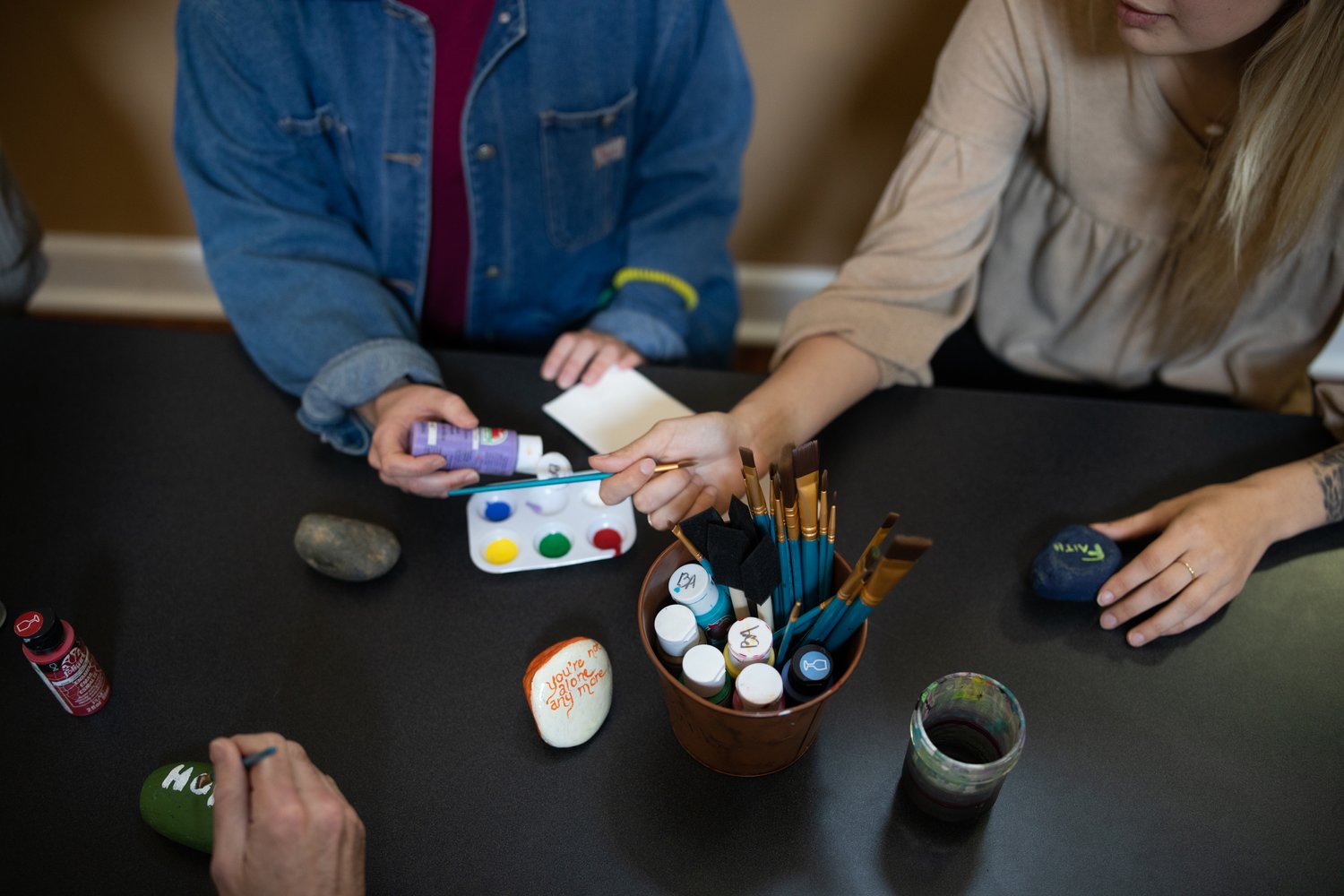 Painting inspirational words on stones with brushes
