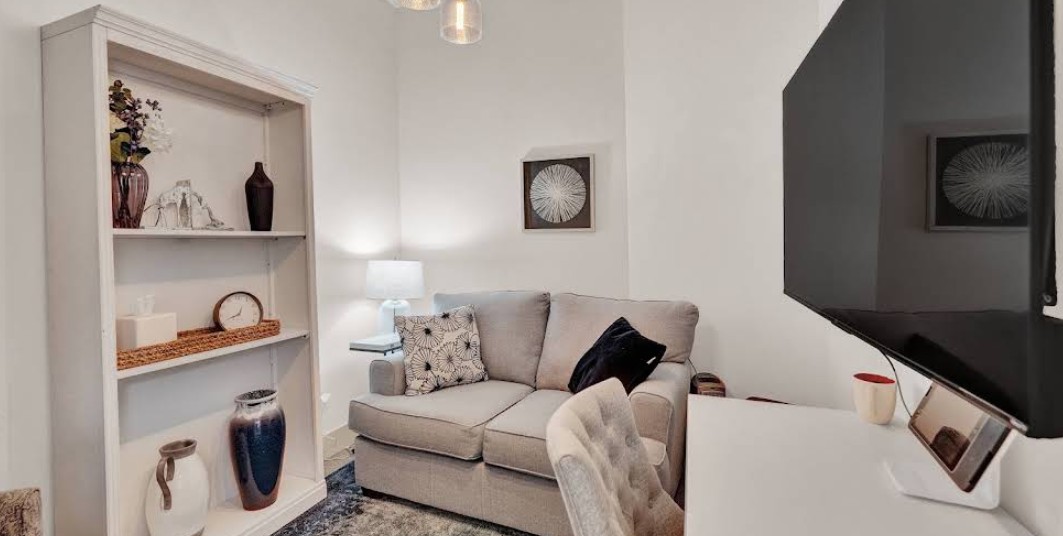 Private therapy room with loveseat, desk, and television