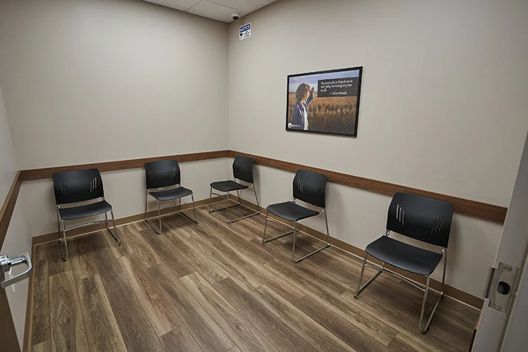 Small waiting area at BrightView Health Marion with five black chairs arranged around the walls, framed recovery artwork, and wood-look flooring