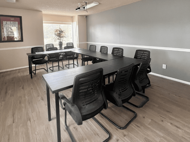 circle of chairs with a whiteboard and large window