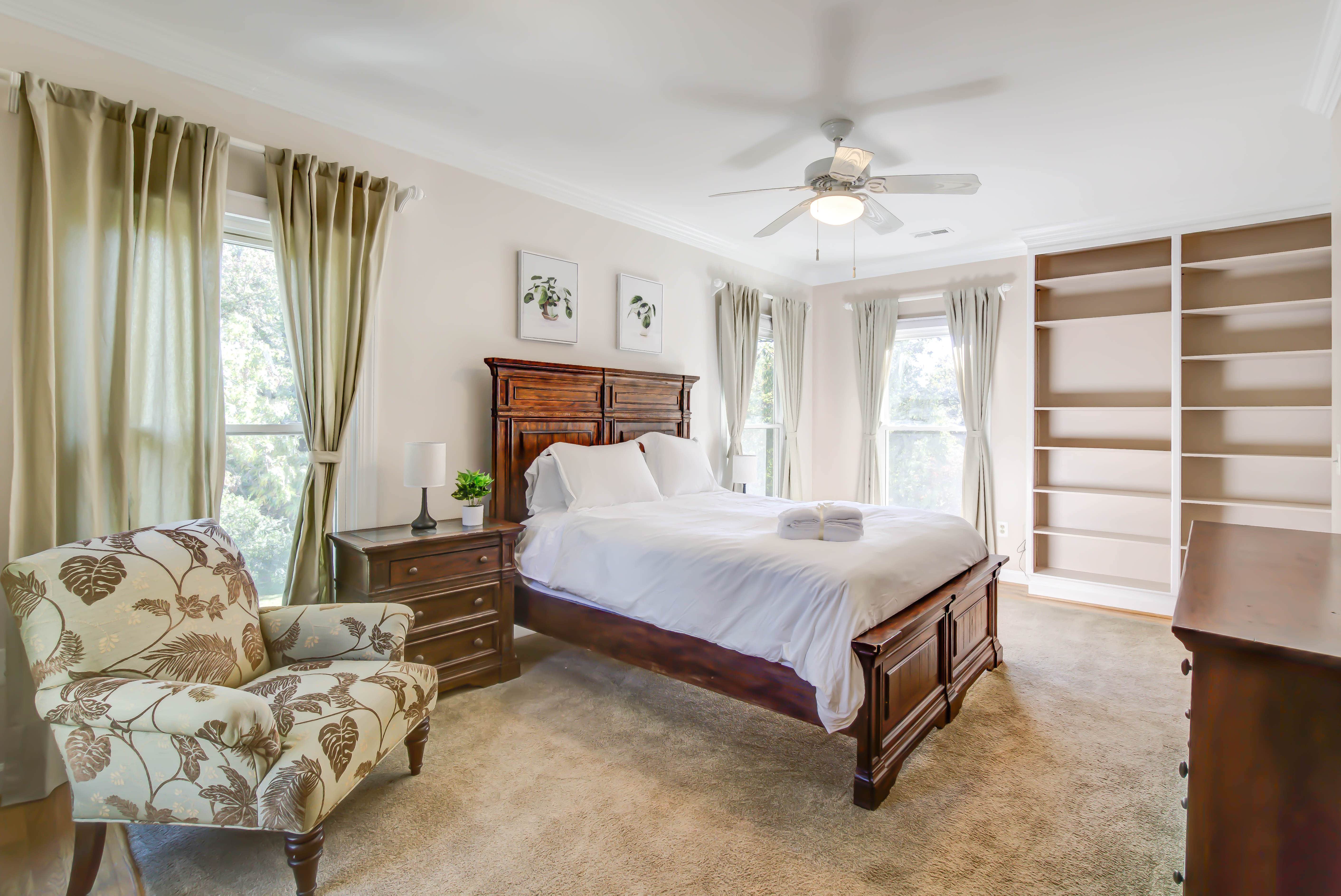 Bedroom with white bedding, wood furniture, and bookshelf