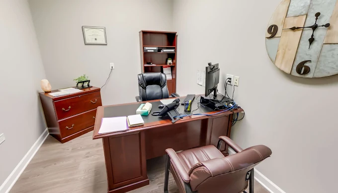 Small office with desk, computer, and black chairs